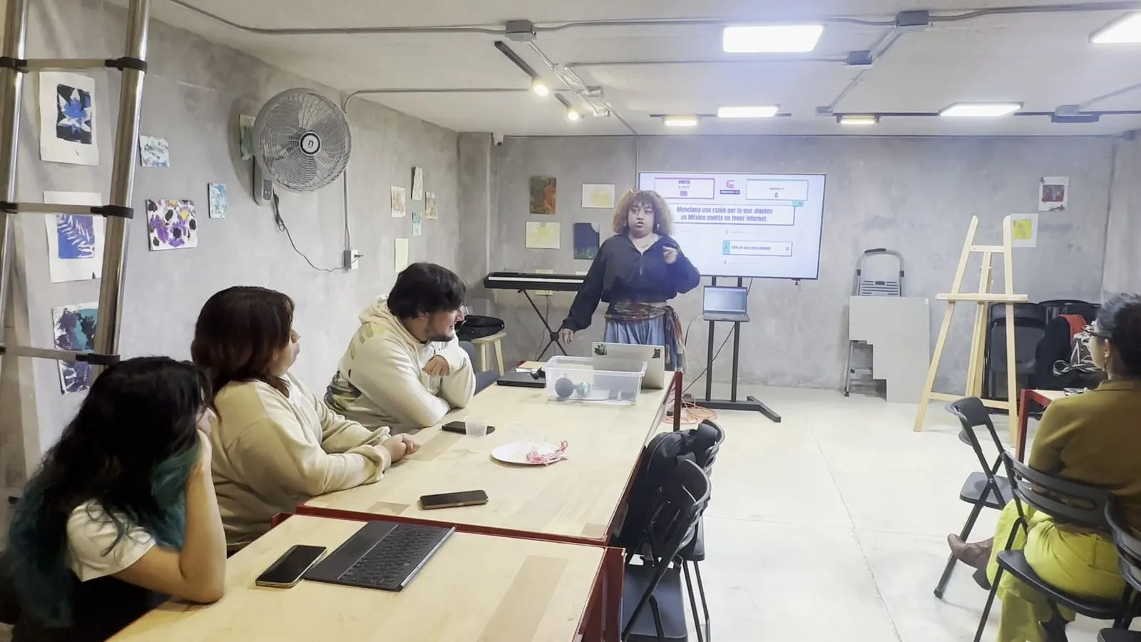 Integrantes de un equipo conversan en la mesa durante la ronda, con la TV al fondo.